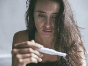 Mulher triste segurando teste de gravidez negativo