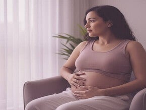 Mulher pós-parto, com toque suave na barriga, em reflexão sobre seu corpo em recuperação. Foco em autoaceitação e cuidado.