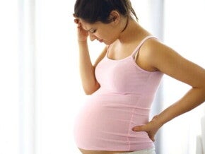 Mulher grávida com dor intensa e desconforto, possivelmente apresentando sintomas de descolamento de placenta.