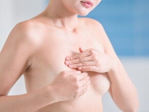 Mulher avaliando os próprios seios, o que pode estar relacionado ao reconhecimento da condição de mama tuberosa e suas características de formato.