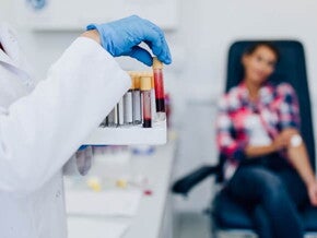 Mulher manuseando tubos de ensaio com amostras de sangue Mulher manuseando tubos de ensaio com amostras de sangue
