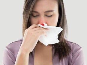 Mulher grávida com os olhos fechados, segurando um lenço de papel para estancar um sangramento no nariz. O lenço está com uma mancha de sangue. A imagem mostra a condição de nariz sangrando na gravidez. Mulher grávida com os olhos fechados, segurando um lenço de papel para estancar um sangramento no nariz. O lenço está com uma mancha de sangue. A imagem mostra a condição de nariz sangrando na gravidez.