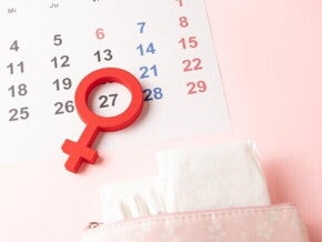 Calendário menstrual com o símbolo de feminino indicando o dia da ovulação e o período fértil 