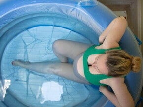 Visão superior de uma gestante dentro de uma piscina inflável de parto, ilustrando a opção do parto na água.