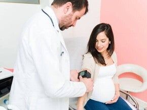 Um profissional de saúde realizando um exame em uma gestante sentada.