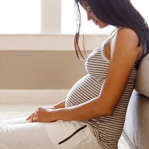 Mulher grávida sentada no chão. Mudanças nos seios durante a gravidez.