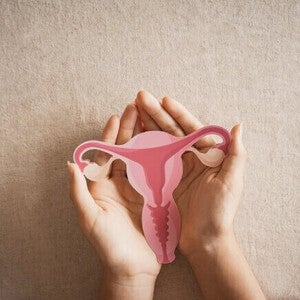 Mulher segurando útero, sistema reprodutor feminino, saúde da mulher, SOP, conceito ginecológico.
