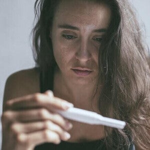 Mulher triste segurando teste de gravidez negativo