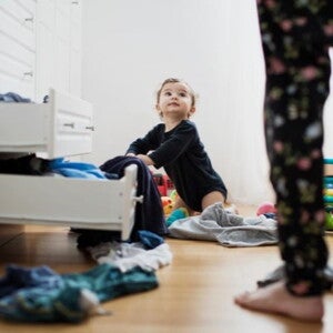 young child looking through clothes drawers