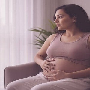 Mulher pós-parto, com toque suave na barriga, em reflexão sobre seu corpo em recuperação. Foco em autoaceitação e cuidado.