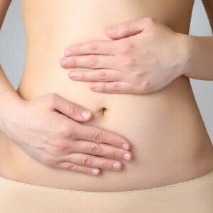 Uma mulher com as mãos sobre a região abdominal Uma mulher com as mãos sobre a região abdominal