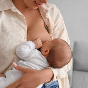 Uma mãe amamentando seu bebê, representando a importância da dieta de exclusão de proteína do leite de vaca para o bebê alérgico que está em aleitamento materno.