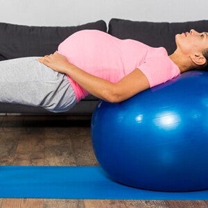 Gestante com as costas apoiadas em uma bola inflável praticando fisioterapia pélvica. Gestante com as costas apoiadas em uma bola inflável praticando fisioterapia pélvica.