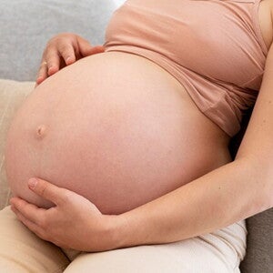 Gestante sentada com a mão na barriga Gestante sentada com a mão na barriga
