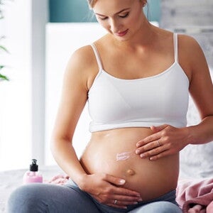 gestante sentada passando creme na barriga gestante sentada passando creme na barriga