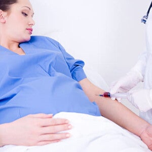 gestante vestindo roupa de hospital, ao lado um profissional de enfermagem colhendo gestante vestindo roupa de hospital, ao lado um profissional de enfermagem colhendo