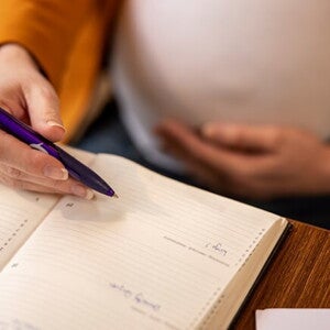 Imagem de um mulher grávida fazendo anotações em uma agenda Imagem de um mulher grávida fazendo anotações em uma agenda
