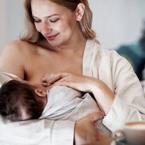 Mãe olhando para o seu bebê enquanto ele se alimenta no peito