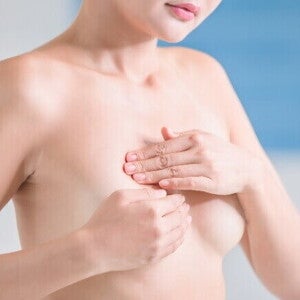 Mulher avaliando os próprios seios, o que pode estar relacionado ao reconhecimento da condição de mama tuberosa e suas características de formato.