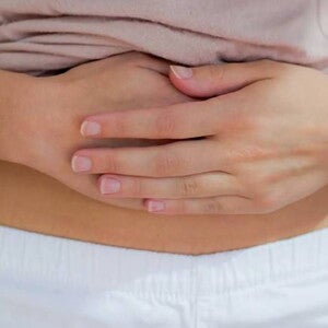 Mulher com cólica menstrual pressionando com força a região abaixo do umbigo. Mulher com cólica menstrual pressionando com força a região abaixo do umbigo.