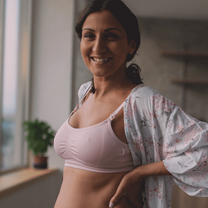 Confident looking woman in a lactation bra, checking her post partum body.