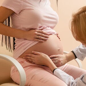 Médica obstetra apalpando a barriga de uma mulher grávida Médica obstetra apalpando a barriga de uma mulher grávida