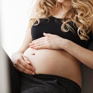 Gestante sentada com as mãos sobre a sua barriga Gestante sentada com as mãos sobre a sua barriga