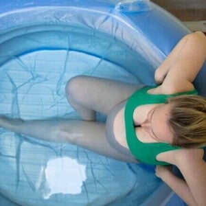 Visão superior de uma gestante dentro de uma piscina inflável de parto, ilustrando a opção do parto na água.