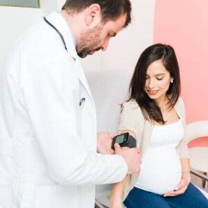 Um profissional de saúde realizando um exame em uma gestante sentada. Um profissional de saúde realizando um exame em uma gestante sentada.