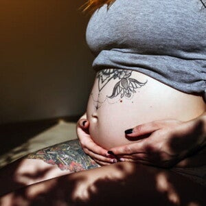 imagem de uma mulher grávida com tatuagem próxima a barriga imagem de uma mulher grávida com tatuagem próxima a barriga