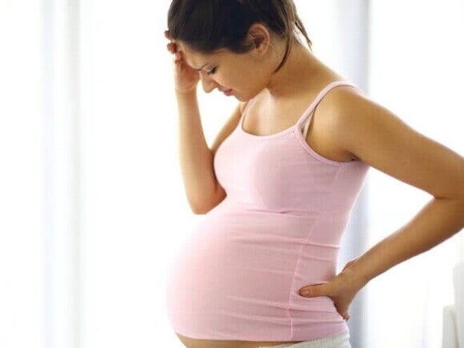 Mulher grávida com dor intensa e desconforto, possivelmente apresentando sintomas de descolamento de placenta.