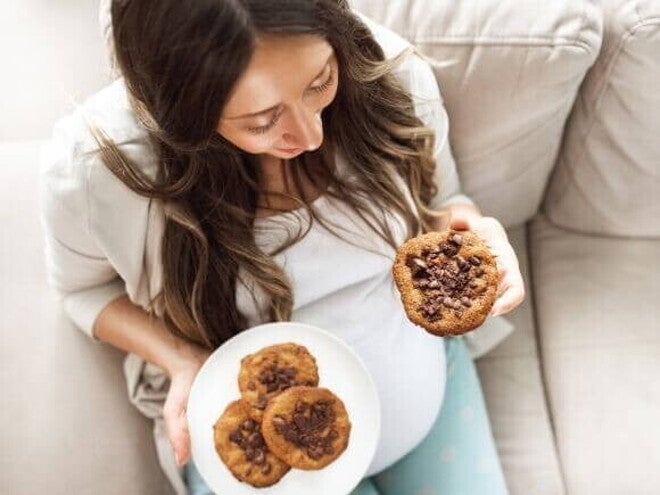 mulher grávida segurando um prato com cookies de chocolate e sorrindo. mulher grávida segurando um prato com cookies de chocolate e sorrindo.