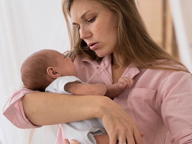 Mulher com blusa rosa carregando o recém-nascido no colo Mulher com blusa rosa carregando o recém-nascido no colo