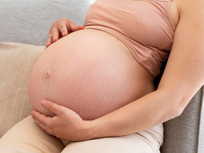 Gestante sentada com a mão na barriga Gestante sentada com a mão na barriga