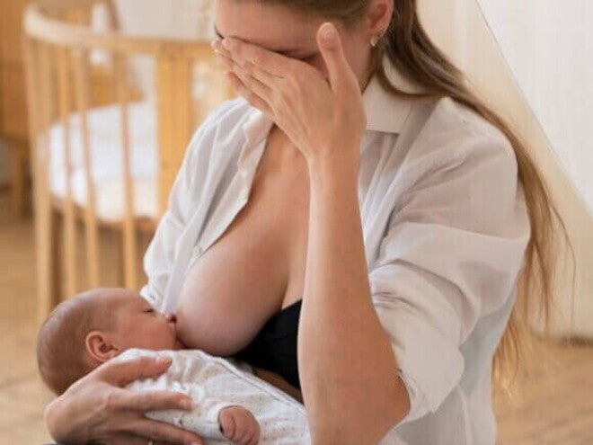 Mulher amamentando bebê recém-nascido com expressão preocupada Mulher amamentando bebê recém-nascido com expressão preocupada