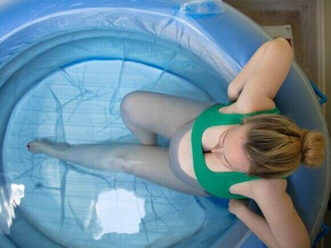 Visão superior de uma gestante dentro de uma piscina inflável de parto, ilustrando a opção do parto na água.