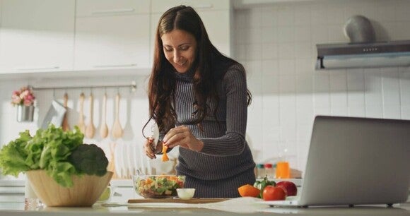 Mulher grávida e celíaca na cozinha preparando uma salada, uma refeição sem glúten