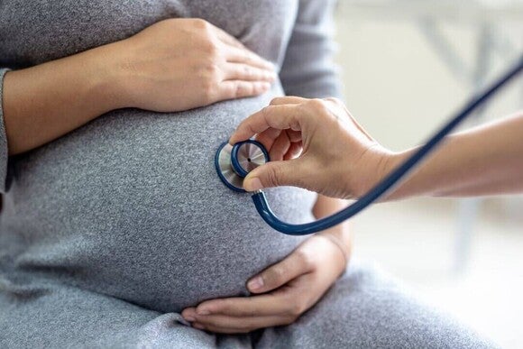 Médico avaliando uma grávida durante uma consulta pré-natal