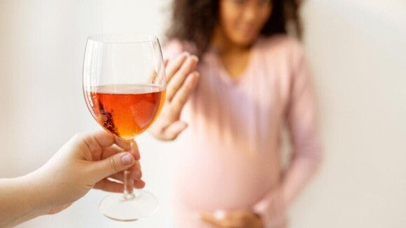 Mulher grávida faz um gesto de "não" com a mão em direção a uma taça de vinho. A imagem representa a abstenção de alimentos para não comer na gravidez, como bebidas alcoólicas, para a saúde do bebê. Mulher grávida faz um gesto de "não" com a mão em direção a uma taça de vinho. A imagem representa a abstenção de alimentos para não comer na gravidez, como bebidas alcoólicas, para a saúde do bebê.