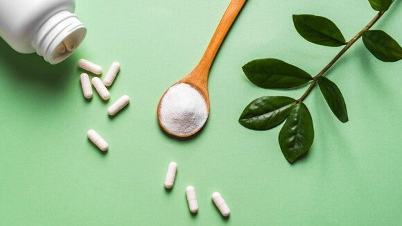 Uma colher de madeira com pó de colágeno e várias cápsulas de suplemento estão dispostas ao lado de um pote branco e folhas verdes. A imagem ilustra a variedade de formas, em pó ou em cápsulas, de colágeno para gestante. Uma colher de madeira com pó de colágeno e várias cápsulas de suplemento estão dispostas ao lado de um pote branco e folhas verdes. A imagem ilustra a variedade de formas, em pó ou em cápsulas, de colágeno para gestante.