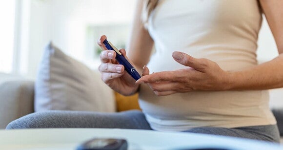 Gestante usando aparelho em formato de caneta para medir seu nível de glicose. Gestante usando aparelho em formato de caneta para medir seu nível de glicose.