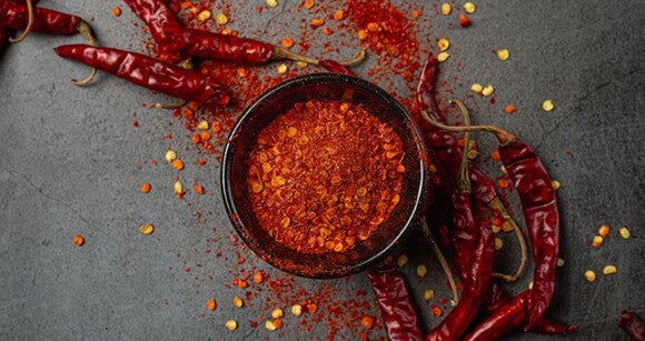 Superfície escura com uma tigela de pimenta em pó Superfície escura com uma tigela de pimenta em pó
