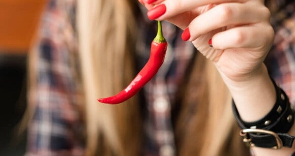 Imagem de uma mulher segurando uma pimenta vermelha Imagem de uma mulher segurando uma pimenta vermelha