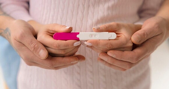 Teste de gravidez de farmácia sendo segurado pelas mãos de uma mulher e um homem. Teste de gravidez de farmácia sendo segurado pelas mãos de uma mulher e um homem.