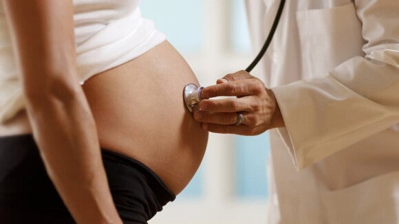 médico examinando barriga de gestante com estetoscópio. médico examinando barriga de gestante com estetoscópio.