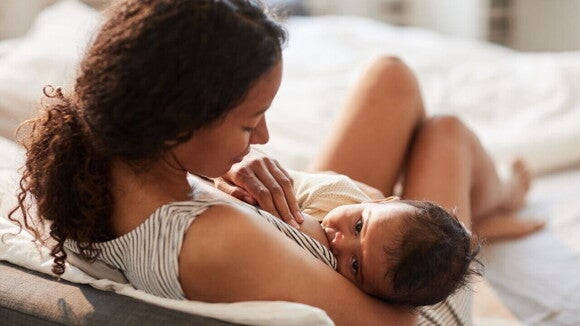 Cena de amamentação entre mãe e bebê, destacando a importância do aleitamento e a possível interferência ou preocupação da mama tuberosa na produção ou fluxo de leite.