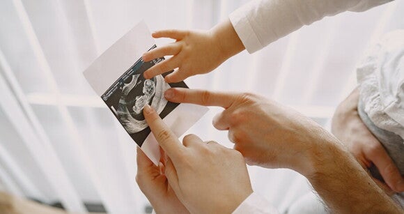 Mãos de membros da família apontando para a imagem de um ultrassom Mãos de membros da família apontando para a imagem de um ultrassom