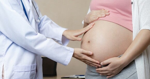 Médico examinando barriga de gestante.