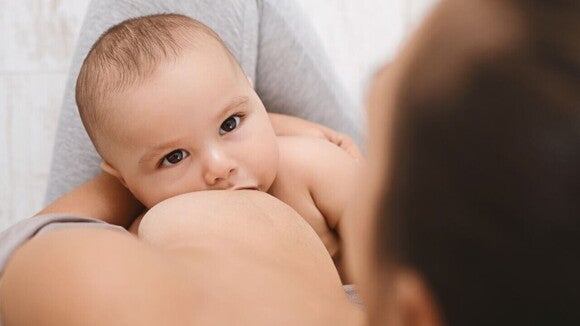 Close-up de um bebê sendo amamentado, destacando o momento de nutrição.