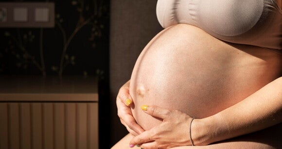 Uma mulher grávida usando um sutiã, mostrando sua barriga. Uma mulher grávida usando um sutiã, mostrando sua barriga.